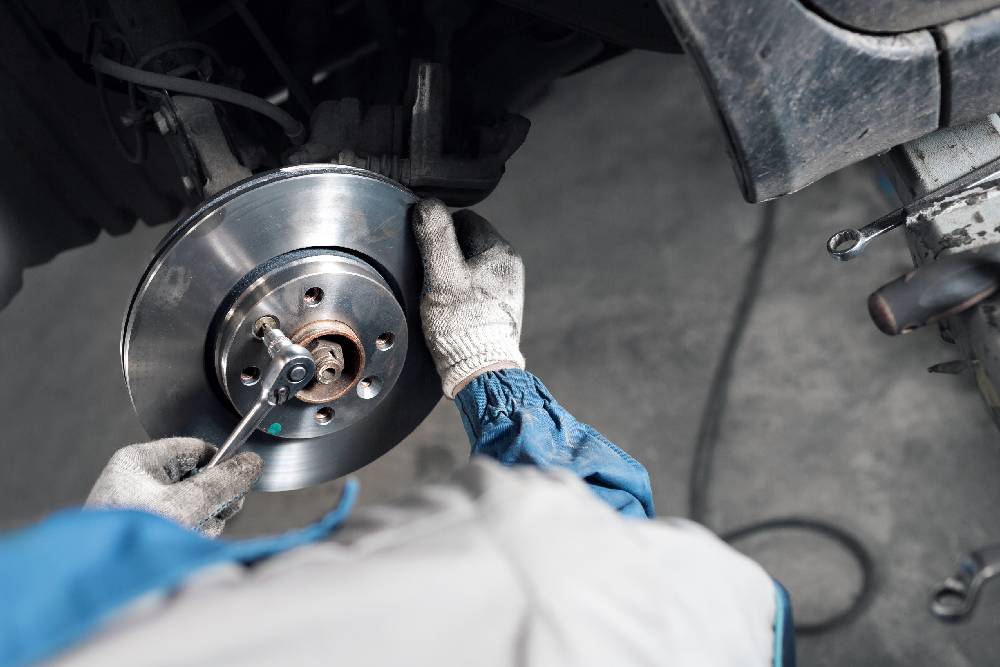 Brakes Car mechanic hands replace brakes in garage.