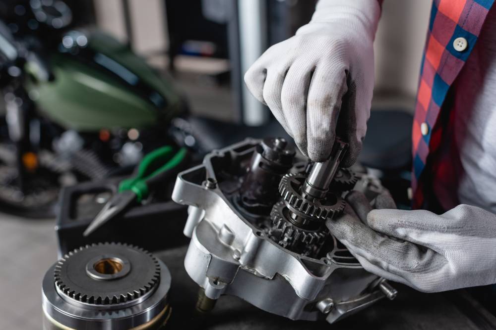 Transmission Services partial view of technician in gloves examining disassembled motorbike gearbox